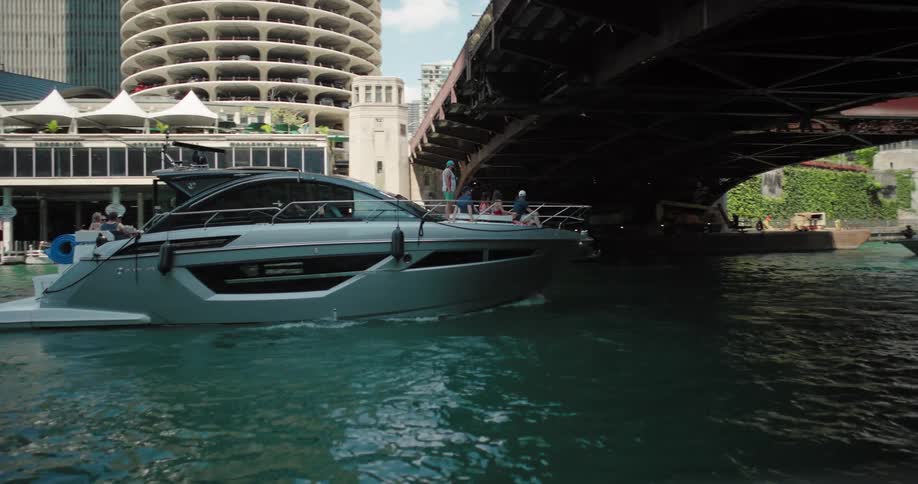 Boat sails on a river surrounded by modern buildings and urban structures