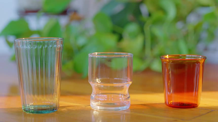 Three empty glass cups sit on a table in daylight