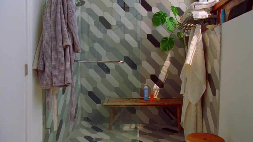 A stylish modern bathroom features a large glassenclosed walkin shower decorated with a bold geometric tile pattern in shades of grey