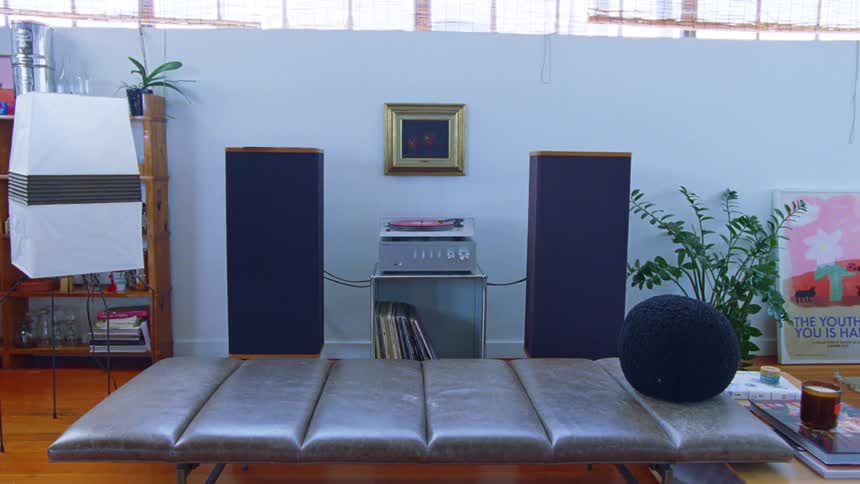 A vintage stereo system with a turntable and tall speakers serves as the focal point in a bright stylishly decorated modern living room or loft