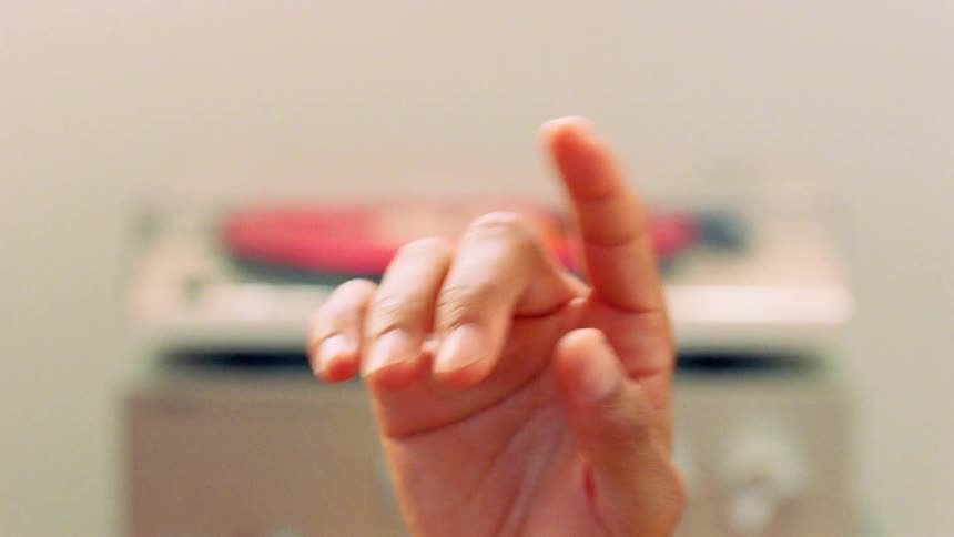 Hand swaying with the music being played from a vinyl record on a retro stereo