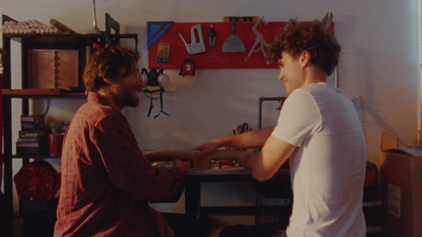 A man and teenager are sanding a piece of wood