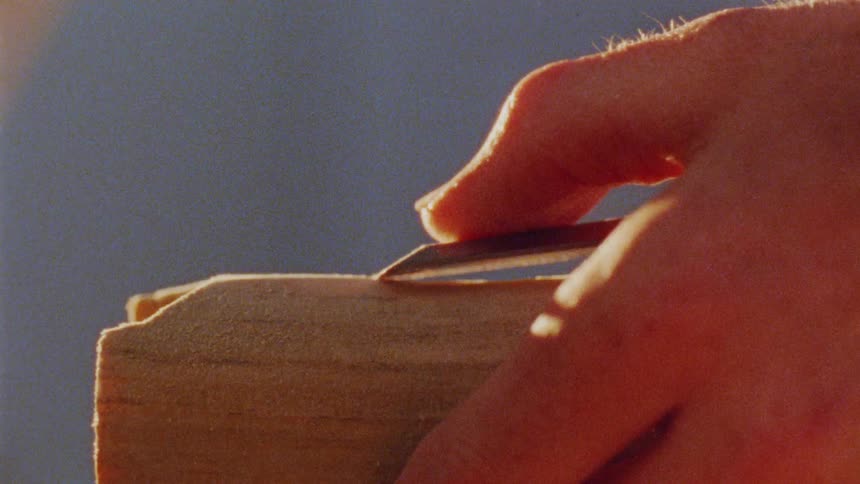 Hand with tool scraping wood