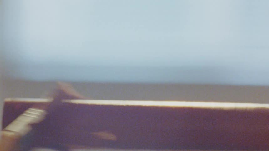 A macro shot shows a hand using a small tool to scrape a thin browncolored substance off a flat surface the substance appears to be applied in a broad thick line and the surface its on has some texture