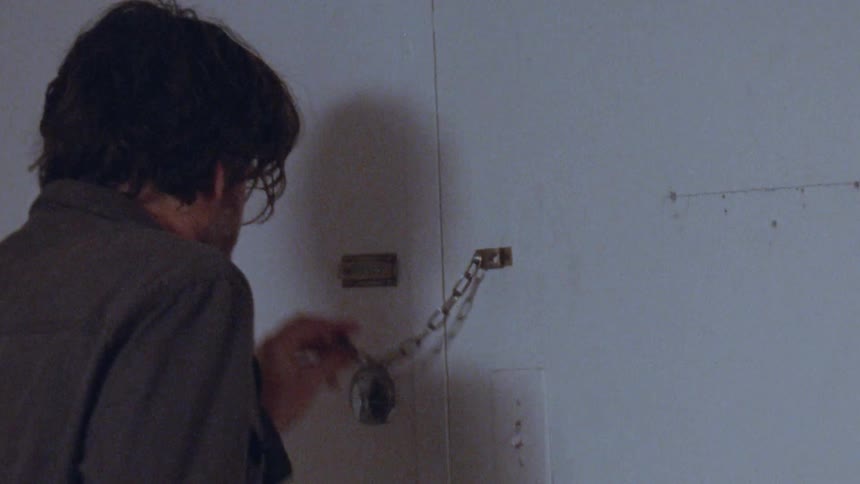 Close up of a middle aged man taking a phone call after quietly locking the door with a chain lock