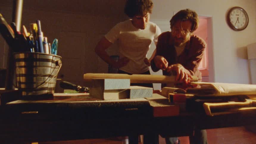 Two people work on a woodworking project at a table