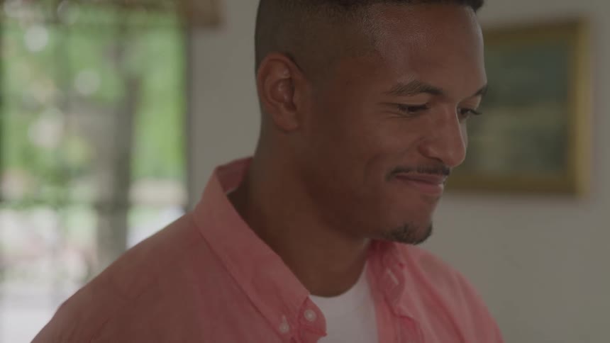 Close up portrait of a young black man standing in a room while conversing during daytime