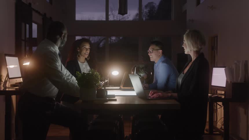 Four people work together around a lit table at night