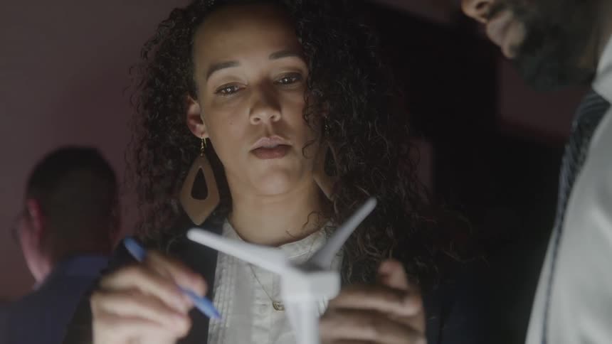 Woman looks at a wind turbine model while talking with a colleague