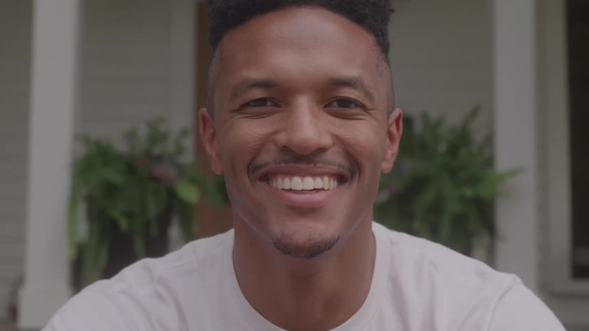 A man sitting in front of a house smiling