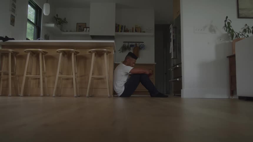Man sitting on the kitchen floor with a weary expression