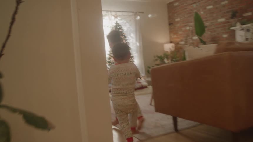 Two young boys in pajamas running toward a christmas tree and grabbing presents