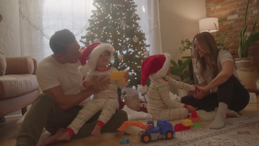 Family with two kids having fun by a christmas tree