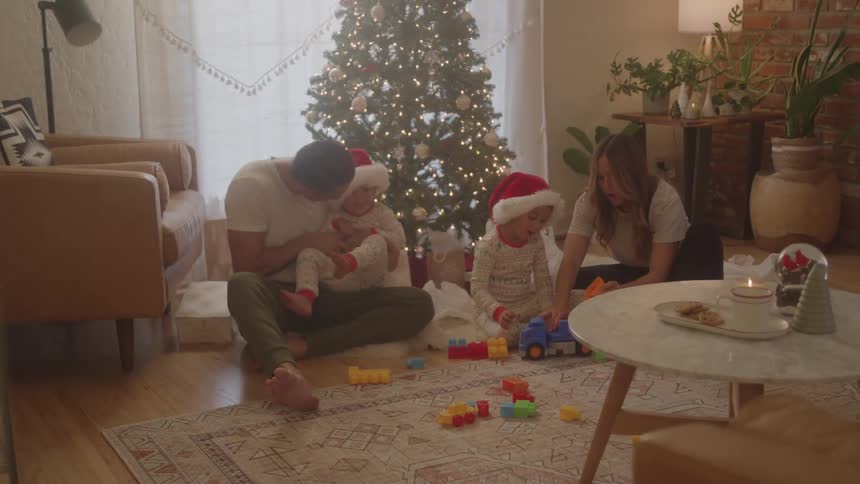 A family play with toys by the christmas tree