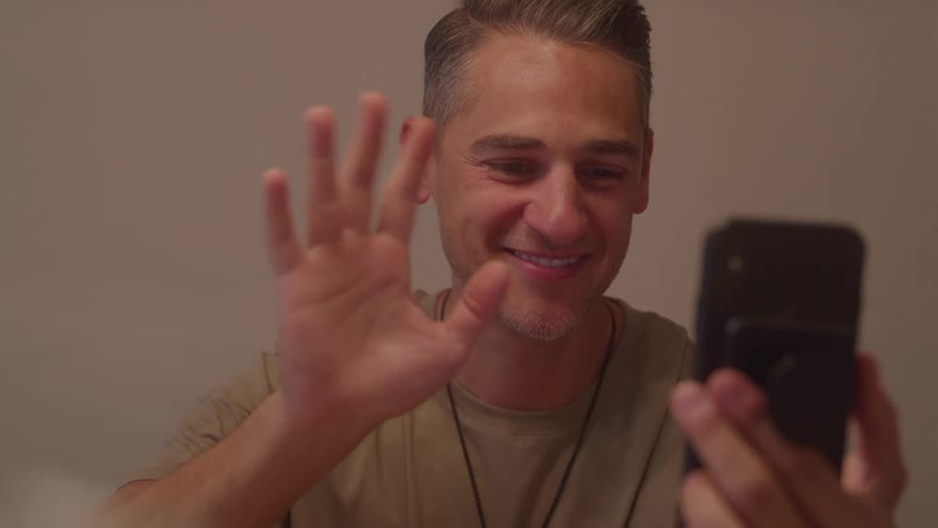 A man on a video call on his phone waving his hand