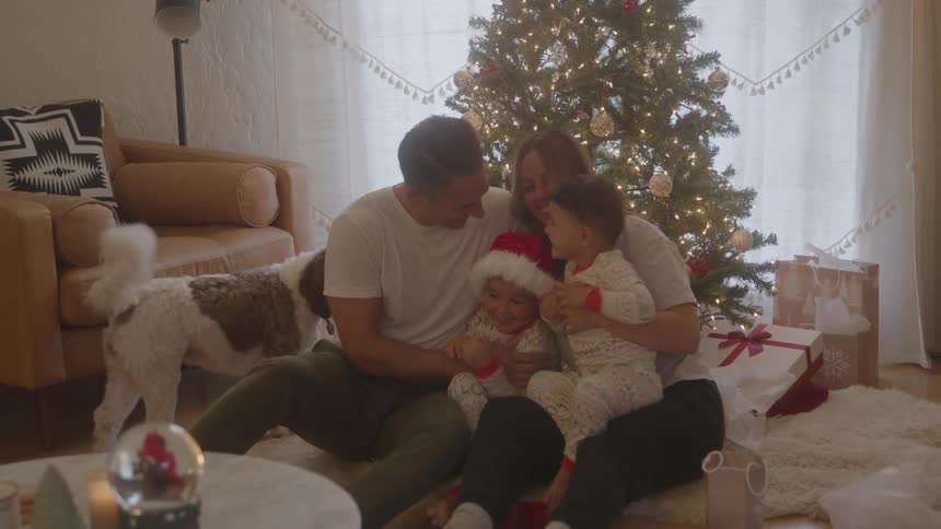 A family gathered at christmas a man a woman two boys and a dog with the parents holding and hugging their children
