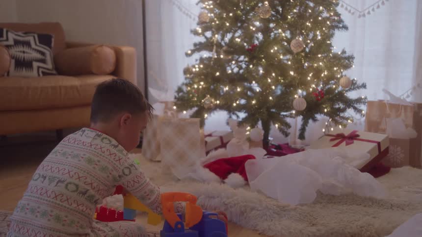 Boy playing with toys near christmas tree in living room