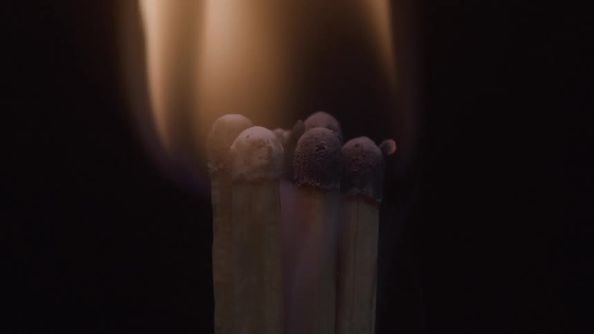 A cluster of matchsticks ignites in a burst of bright flame