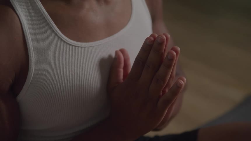 A person sitting on the floor their hands clasped together