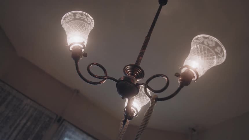 Vintage chandelier with three lit bulbs and decorated glass shades