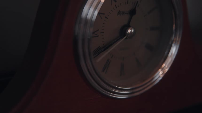 Close up of a ticking table clock in a dark room
