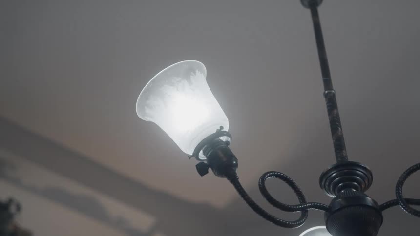 A light bulb on a chandelier flickers on and off continuously