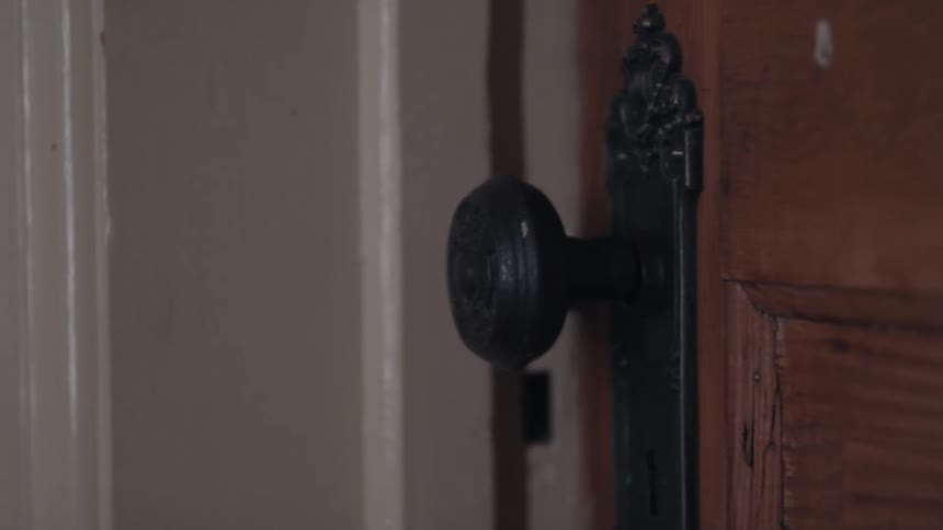 An vintage metal doorknob slowly turns and the door opens