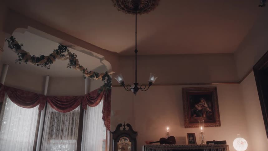 Candlelit vintage living room with a hanging chandelier and draped windows