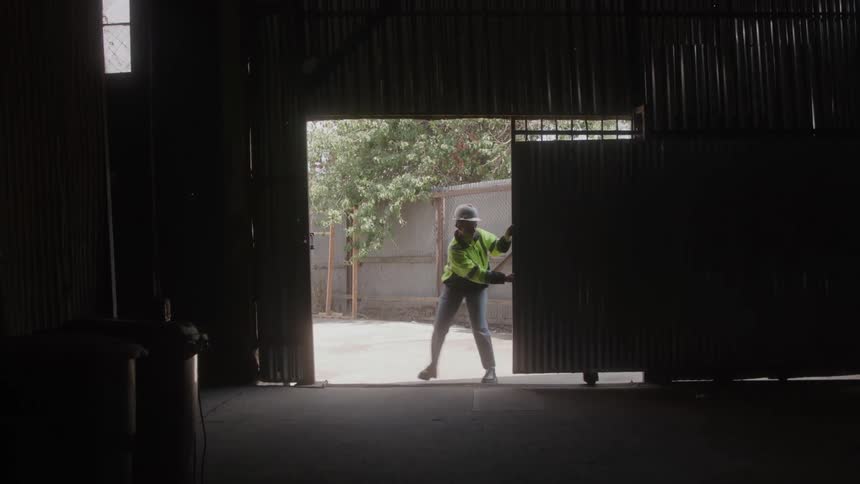 A worker closing the gate of a warehouse or garage