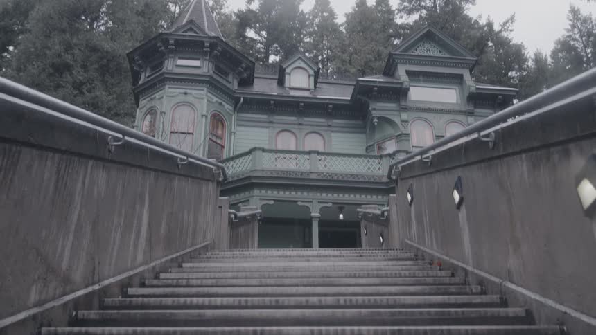 Victorian mansion surrounded by trees on a cloudy day