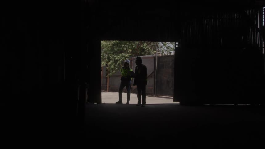 Two workers walk through the empty warehouse