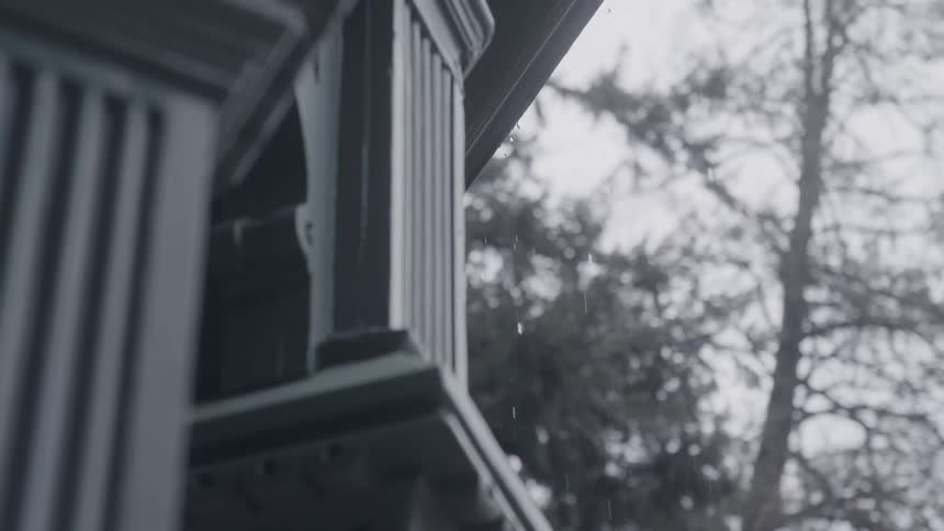 Gutters of an old house drain rainwater on a gray day