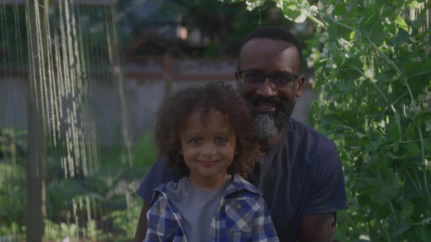 Smiling father and son in garden looking at camera