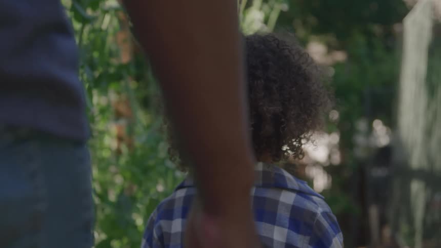 Curlyhaired child wearing a blue plaid shirt in an outdoor setting