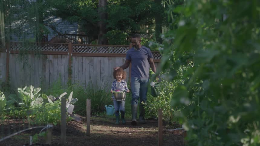 Man and child walking together in the garden carrying buckets