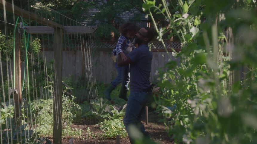 A father lifts his daughter up in the yard