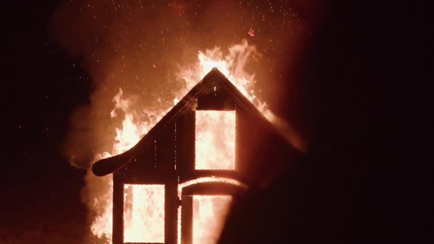 Burning house engulfed in a blaze of flames glowing in the darkness
