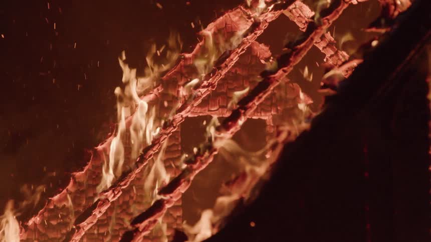 A building is completely engulfed in flames at night with its skeletal structure still standing as it burns