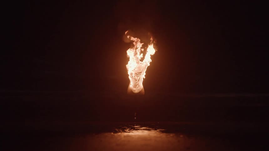 Lit torch isolated in the dark reflecting on the wet ground