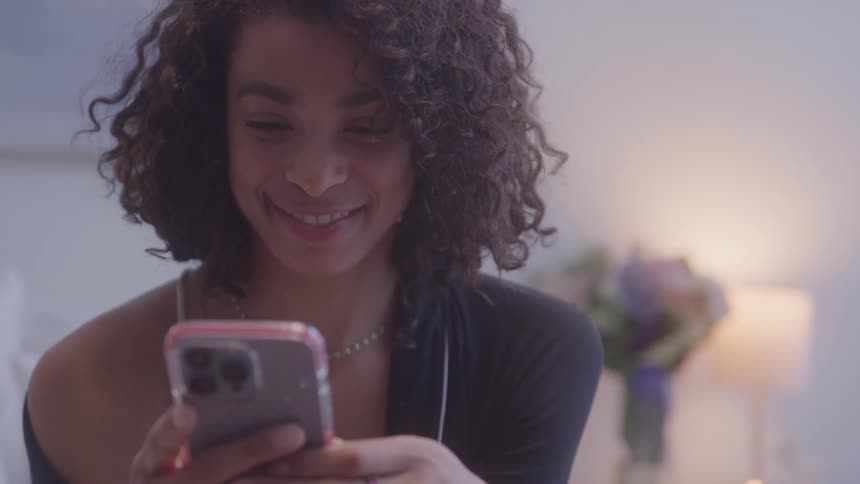 Smiling woman uses her phone with a blurred bouquet in the background