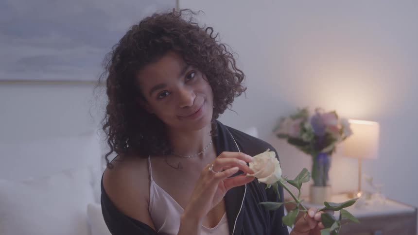 Woman interacting with a white flower in a room