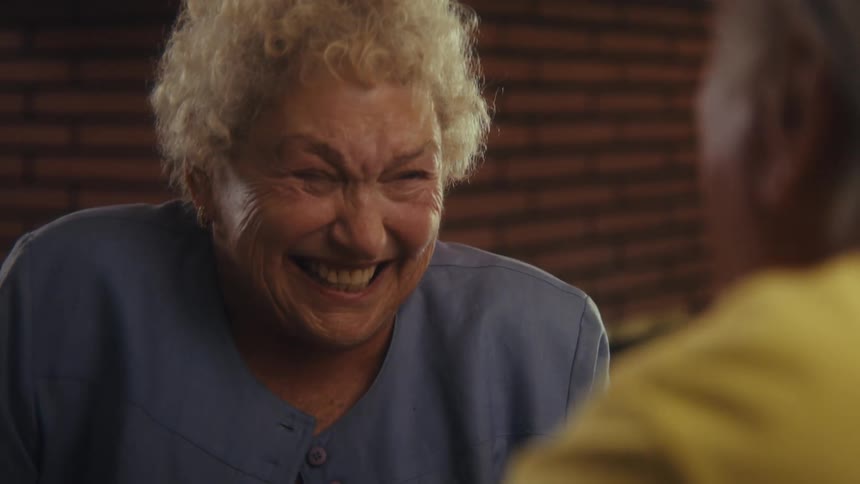 An elderly couple having a discussion while both laugh during their conversation