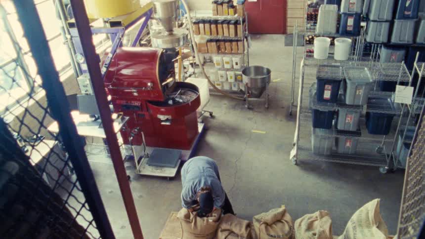 Worker handling sacks of beans in a coffee roastery