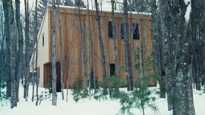Wooden house surrounded by trees in the snow