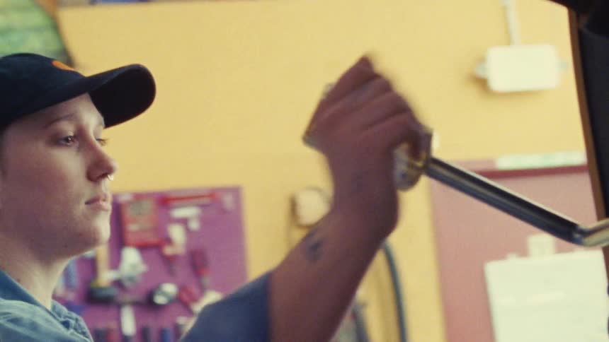 Person adjusting a golden metallic tool in a workshop setting