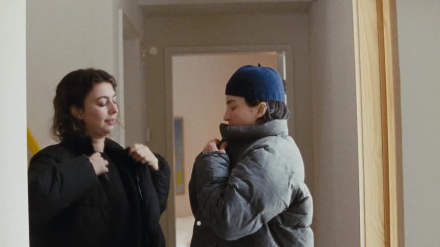 Two people getting ready to leave while putting on coats