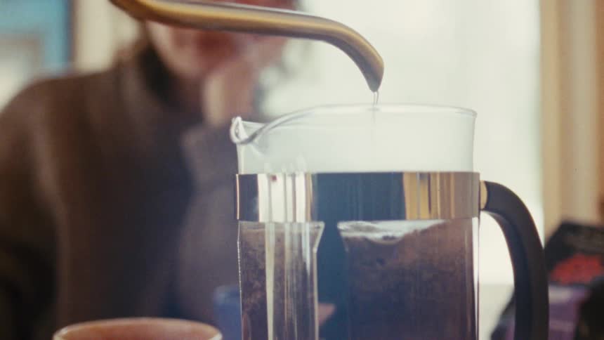 Hot water being poured into a french press with coffee grounds