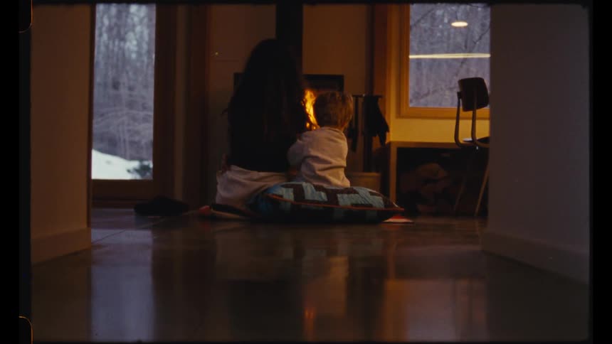 A mother and son sit in front of the fireplace