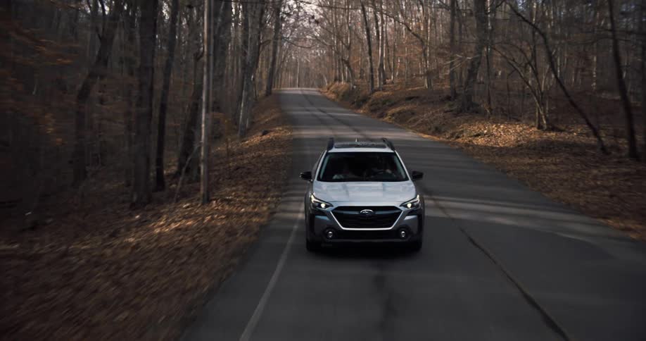 Automobile traveling on a road through the forest on a fall day