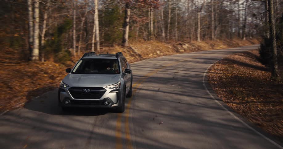 Two people drive a subaru outback along a remote road
